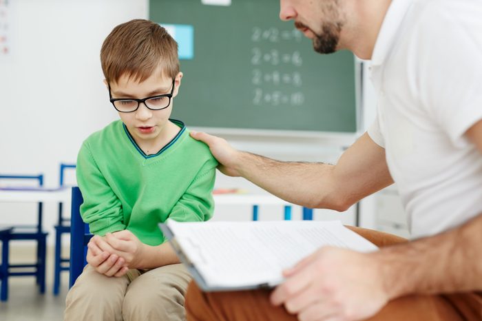 Teacher supporting upset or confused schoolboy during individual lesson