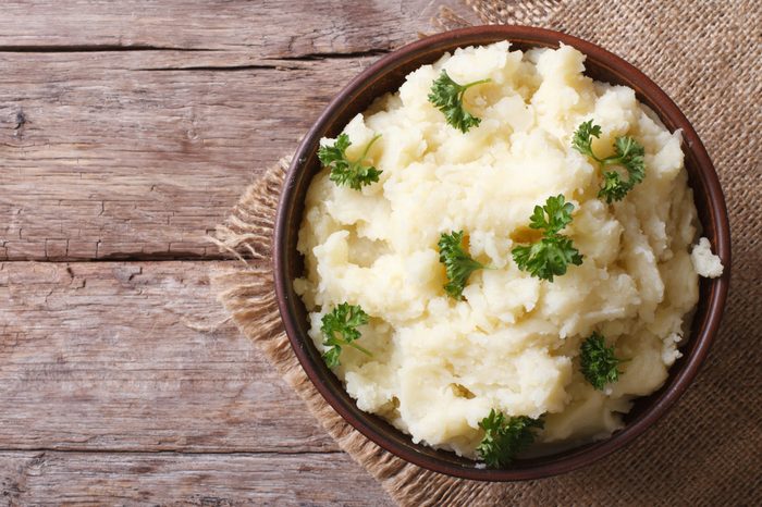 Hot mashed potatoes with parsley in a bowl close-up on the table. horizontal view from above. rustic style 