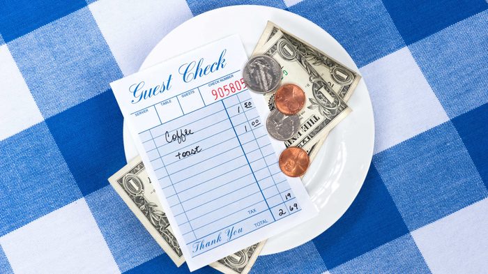 A dining check on a saucer with change from a meal payment.
