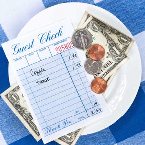 A dining check on a saucer with change from a meal payment.