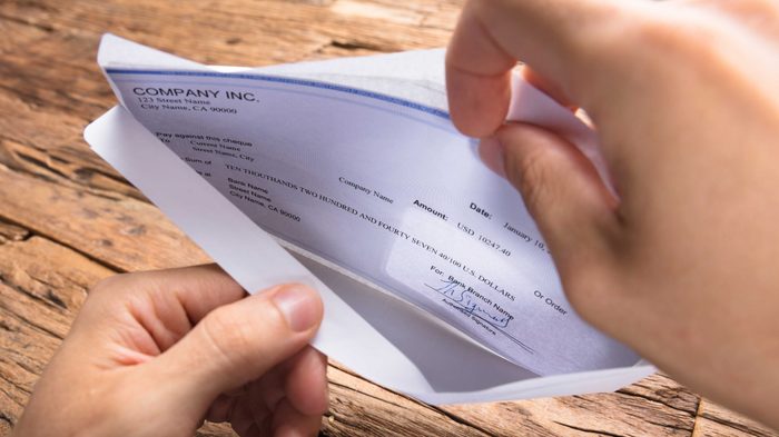 Cropped hands of businessman opening envelope with paycheck