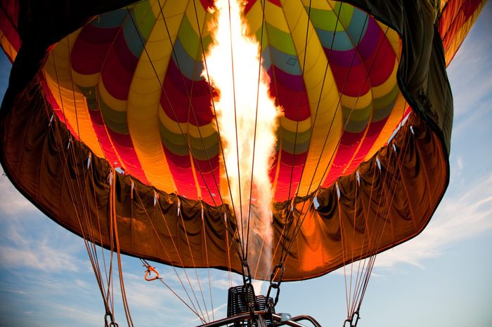 A burner with its super hot flame light up the inside of a colorful hot air balloon as it is inflated for an early morning flight.