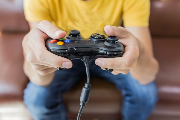 An Asian young man holding game controller playing video games