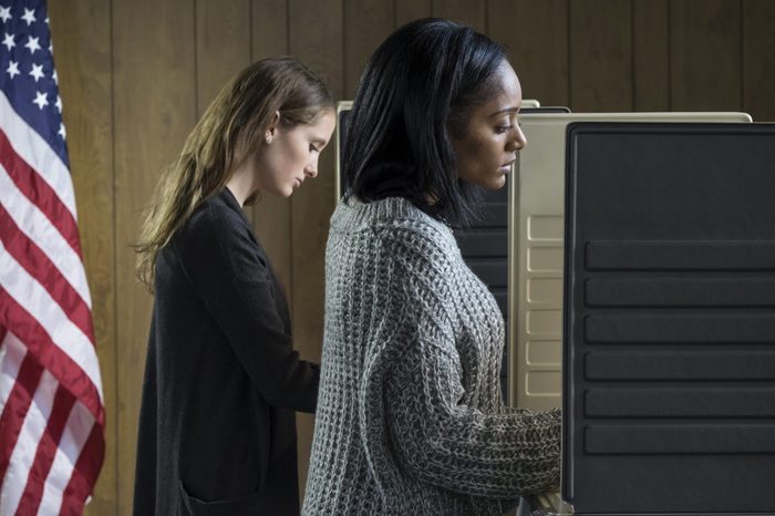 Two young adult women voting in a voting booth