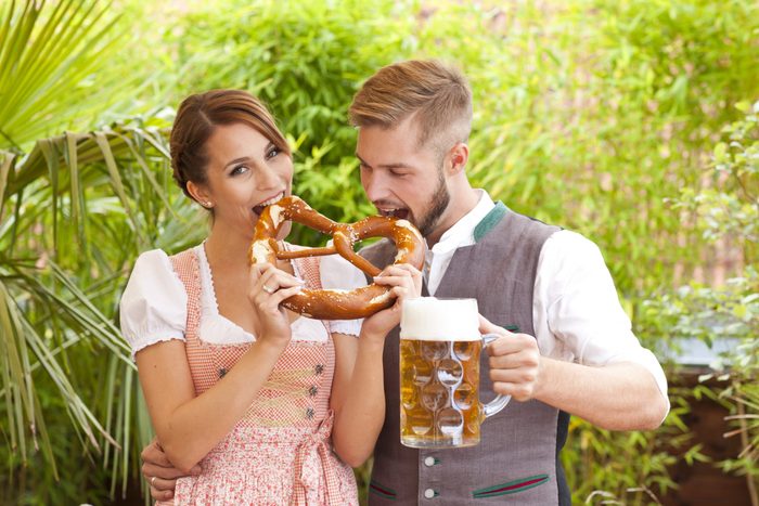 Bavarian couple in traditional costume with beer and brezel outdoor in a beergarden