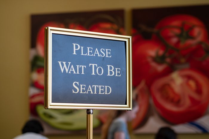 A please wait to be seated sign standing at the front of a restaurant