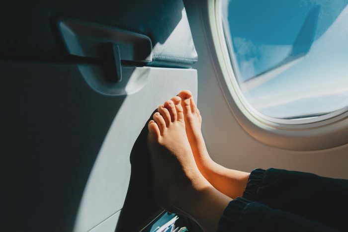 barefoot on the back of an airplane seat