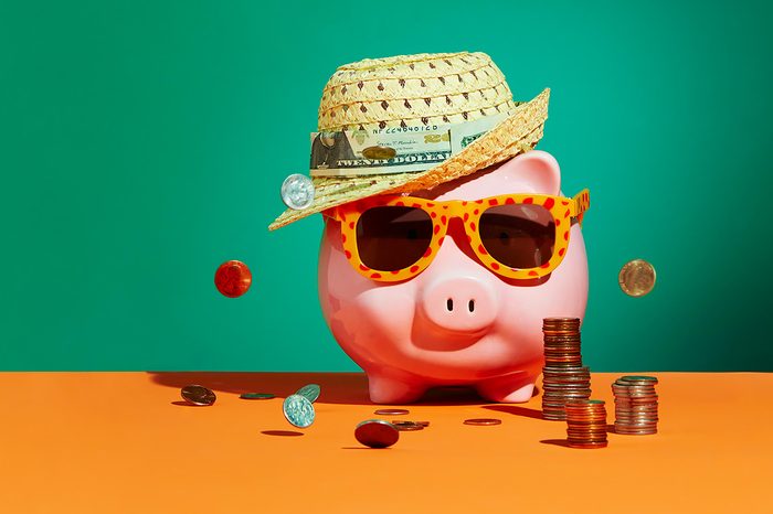piggy bank in a straw hat and sunglasses surrounded by money concept photograph by Sarah Anne Ward