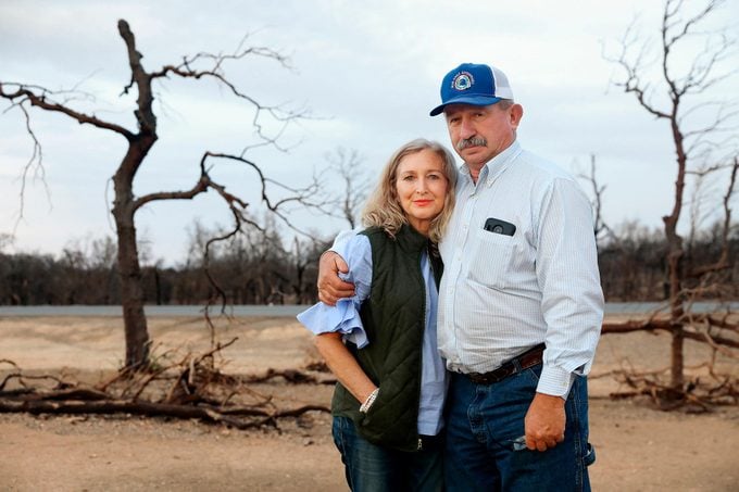 Don Andrews stands with his wife in front of torched trees