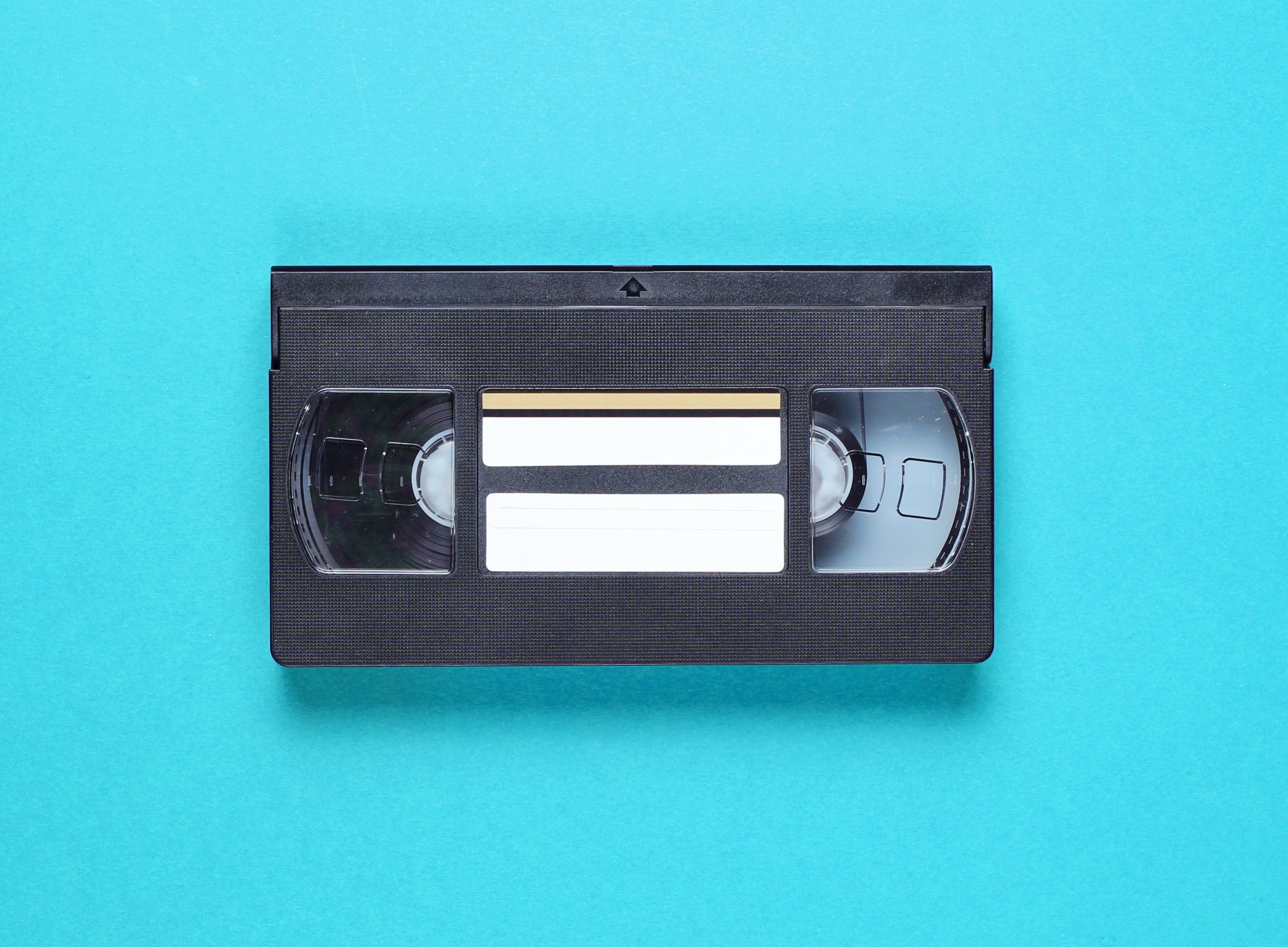 Pop culture retro attributes 80s, video cassette on blue background. Top view