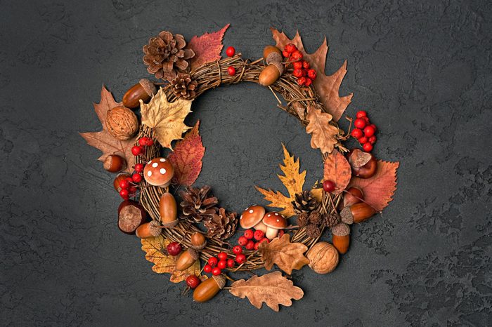 Festive autumn Thanksgiving wreath with mushrooms, fall leaves, red berries, acorns on dark background. autumn holiday, fall, thanksgiving, halloween concept. Flat lay, top view, copy space