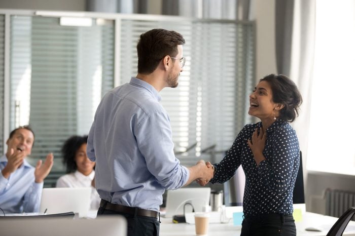 Team leader motivating handshaking female Indian excited employee, congratulate with promotion, business achievement, thank for good result, work, expressing respect, support, colleagues applaud
