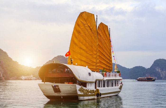 Discover Halong Bay Top Destinations Vietnam view of seascape. Cruise golden Sails liner ship wooden junk sailing rock islands the emerald waters of Ha Long Bay.