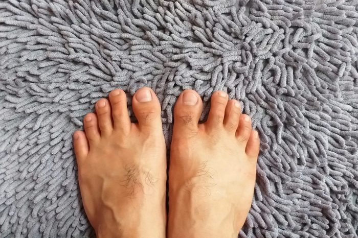 Barefoot on carpet. Two feet standing. Gray carpet. Fluffy carpet. Top view.