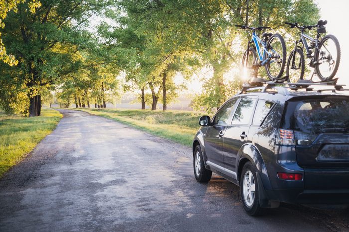 Car with bicycles in the forest road at sunset