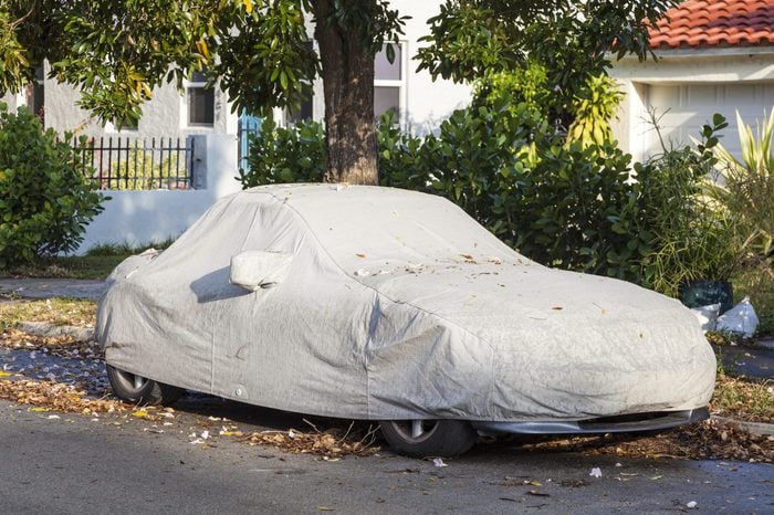 Car under a protective cover parked on the roadside in the city