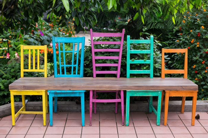 Bench made of five wood chairs in different sizes and colours and wood plank