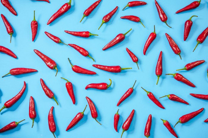 Hot red peppers randomly on blue background,flat lay design.