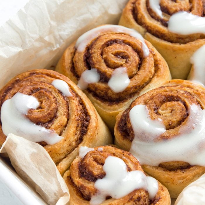 Cinnamon rolls or cinnabons with cream sauce, homemade recipe preparation sweet traditional dessert buns pastry food close up.