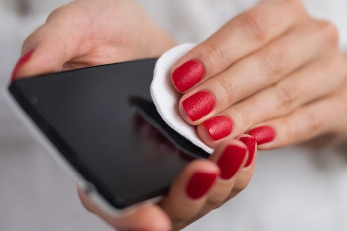 Care and clean the phone with a cotton pad. Female hands holding a mobile phone and wipe the screen cloth.