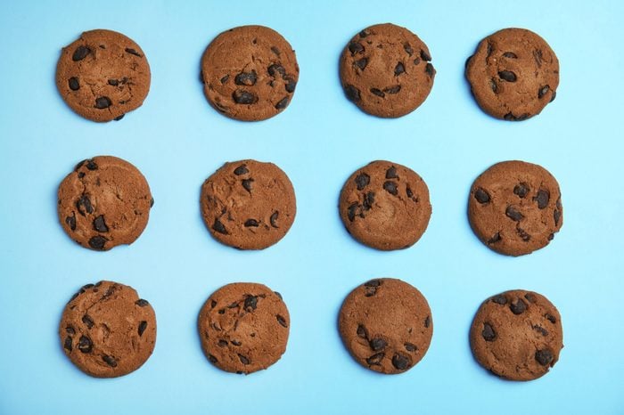 Delicious chocolate chip cookies on color background, flat lay