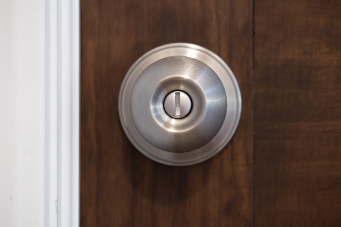closeup, straight on, front view of a silver stainless steel doorknob on a brown wooden entry door to a room