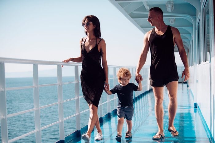 Family travelling on cruise ship on sunny day. Family with cute son on summer vacation. Family rest concept. Father, mother and child walk on deck of cruise liner with sea waves on background.