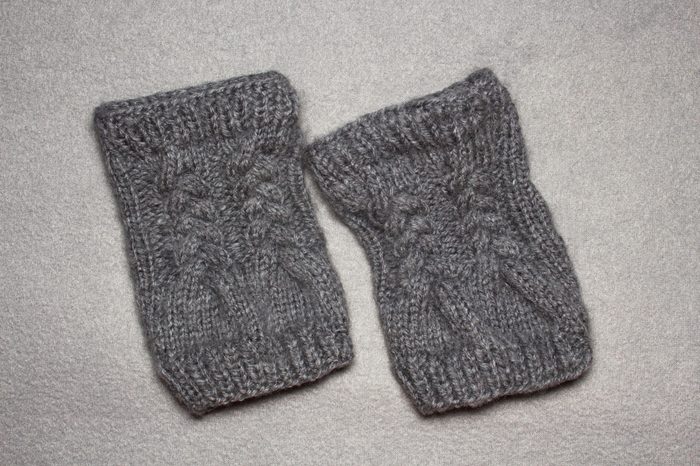 knitting women's gloves mittens without fingers from gray wool yarn, auxiliary needle, braided pattern