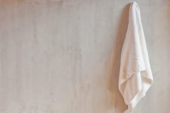 Hanging White Towel draped on Exposed Concrete Wall in the Bathroom