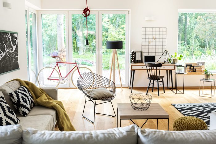 Red bike near the window in bright living room with black and white workspace and terrace view