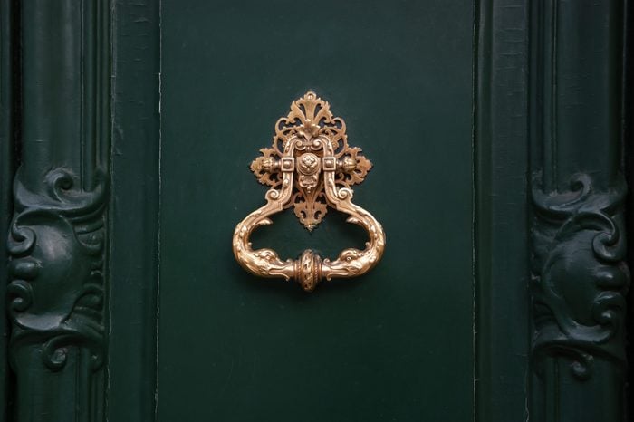 Royal style doorknocker on green door.