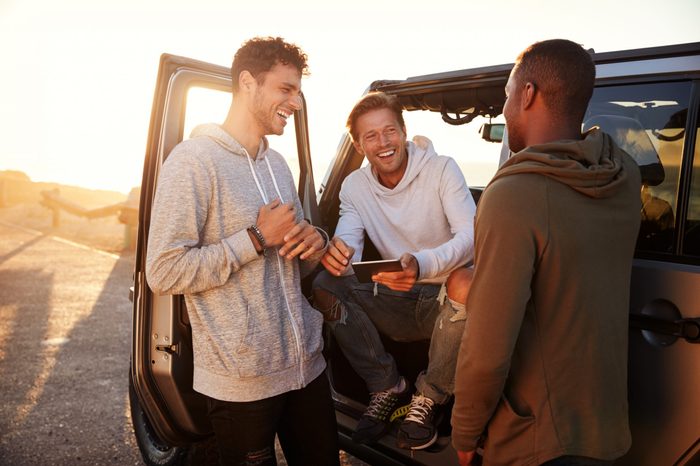Three male friends on a road trip using a tablet computer