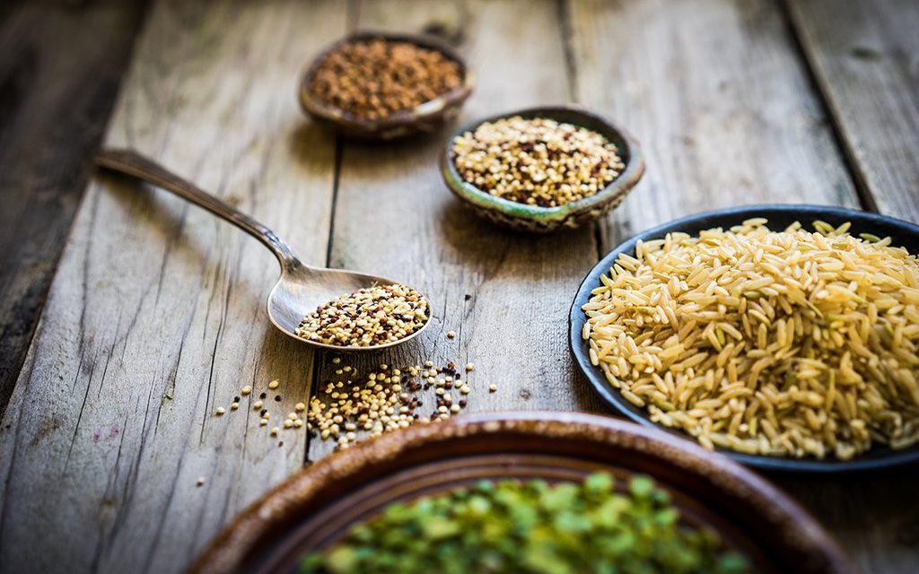 Peas, brown rice, quinoa and buckwheat on wooden background