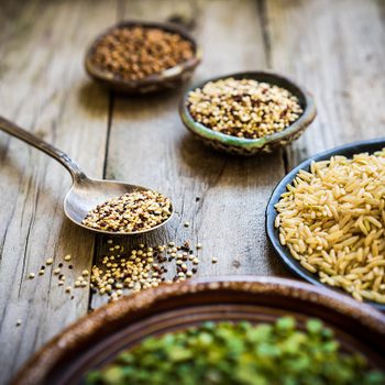 Peas, brown rice, quinoa and buckwheat on wooden background