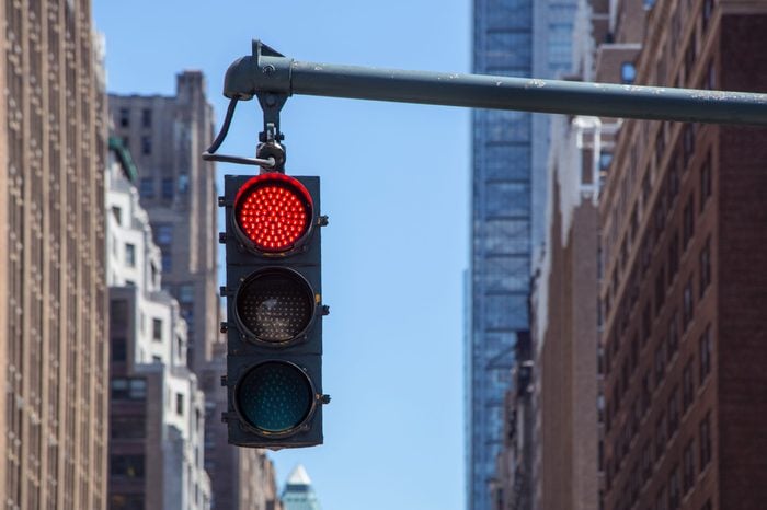 Traffic light closeup with red signal. Traffic light on the background of skyscrapers in New York. Red color traffic light with buildings in the background. Traffic light wallpaper.