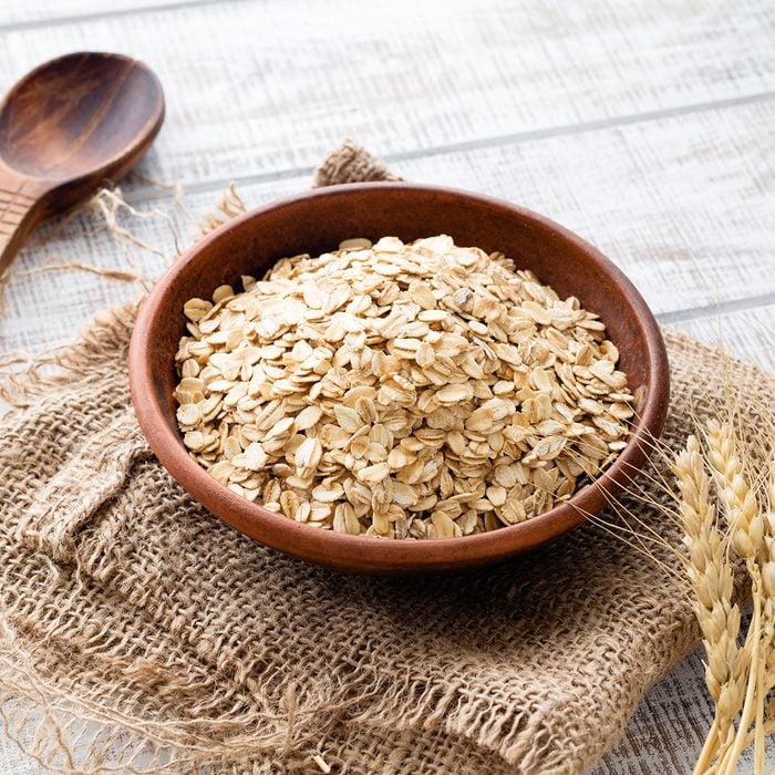 Rolled oats, healthy breakfast cereal oat flakes in bowl on wooden table