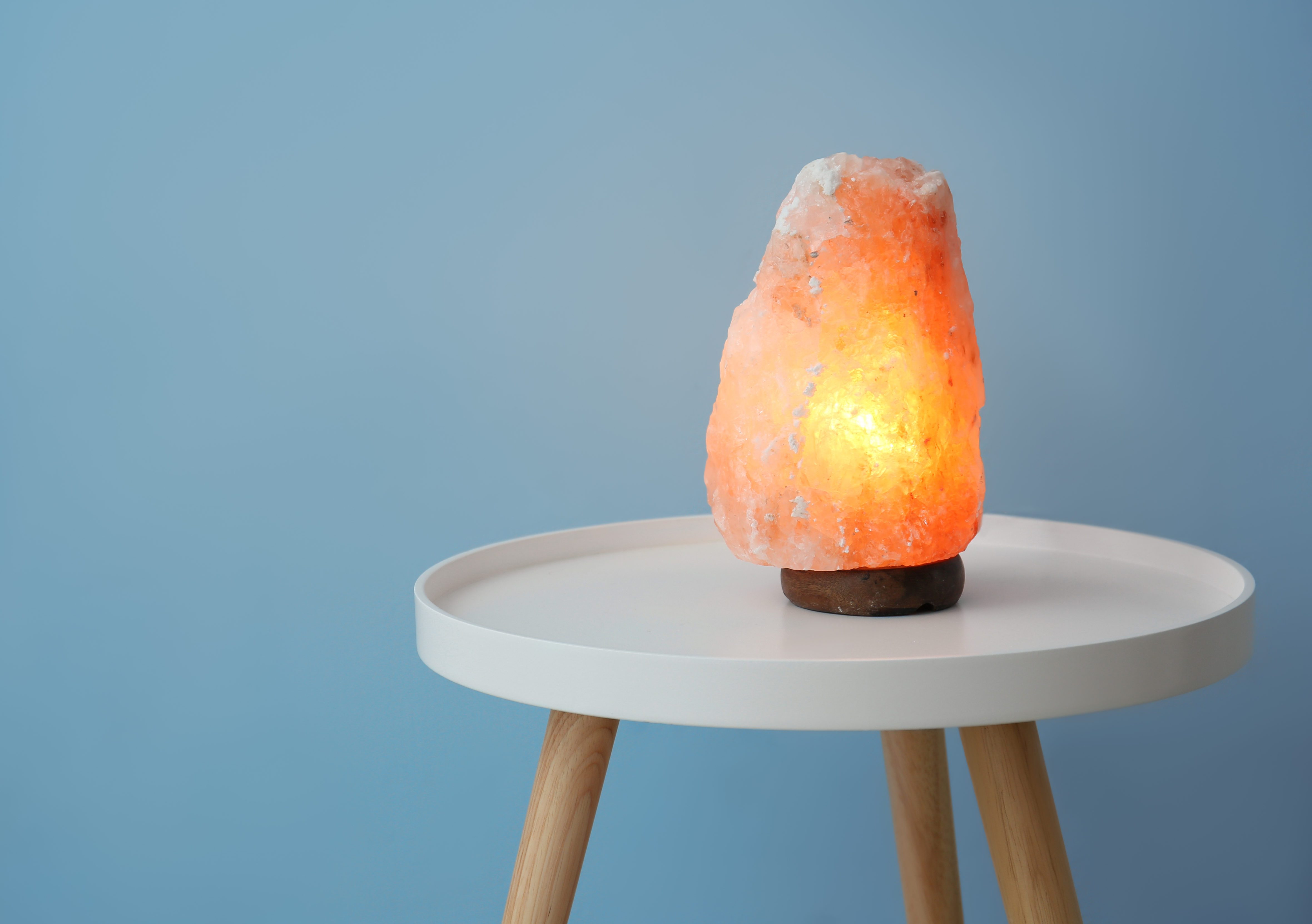 Himalayan salt lamp on table against color background