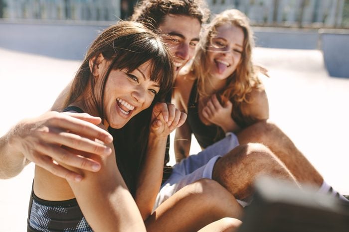 Group of friends posing for a selfie outdoors. Smiling woman taking a selfies while hanging out with friends outdoors.