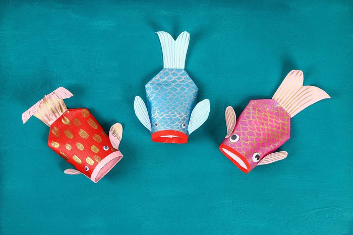 Diy koi carp fish on blue green background. Gift ideas, decor for the Chinese new year. Kid handmade. Carp koi fish of paper, toilet roll, googly eyes. Step by step. Process children crafts. Top view.