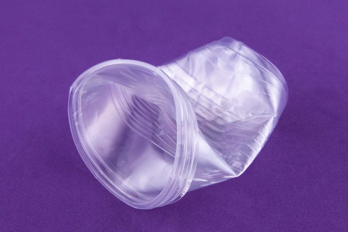 Plastic dishes crumpled cup on a purple background close-up