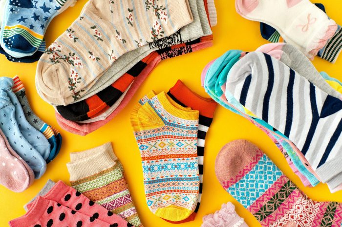 Lots of socks on a yellow background. Colorful socks scattered on a yellow background. Clothing in the form of socks. Knitwear and jersey for autumn and winter.