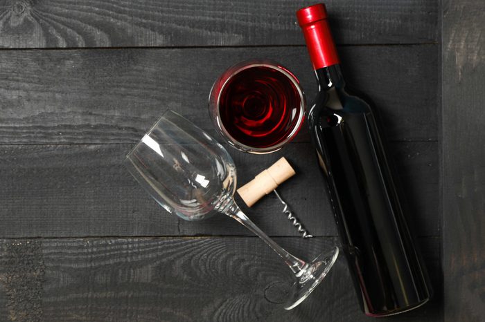 Flat lay composition with bottle of wine, glasses and corkscrew on wooden background, copy space