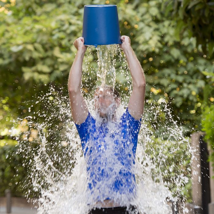 young man pouring ice water bucket on his head getting wet outdoors in internet viral media network challenge campaign to support degenerative sclerosis and neuronal disease and disorder ; Shutterstock ID 214403830; Job (TFH, TOH, RD, BNB, CWM, CM): -