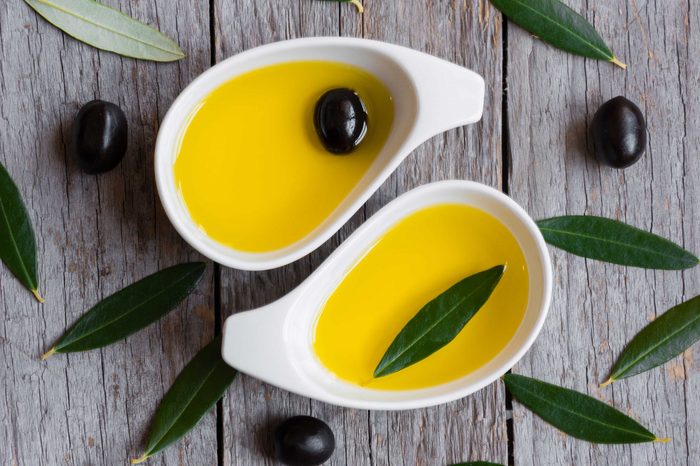 Olive oil with olive leaves on wooden table