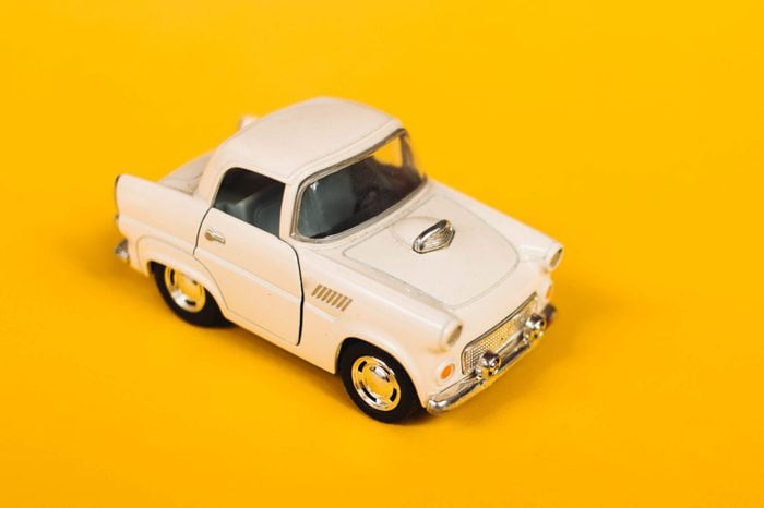 Classic fifties scale model toy car from front view with yellow background