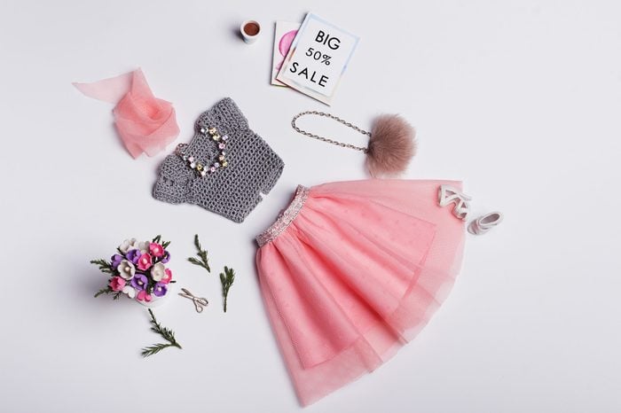 Fashion Concept. Crochet grey blouse and powdery pink tulle skirt with fur handbag, jewelry, shoes, magazines, cup of coffee, bouquet of flowers. Hand-made clothes for 11-inch doll.