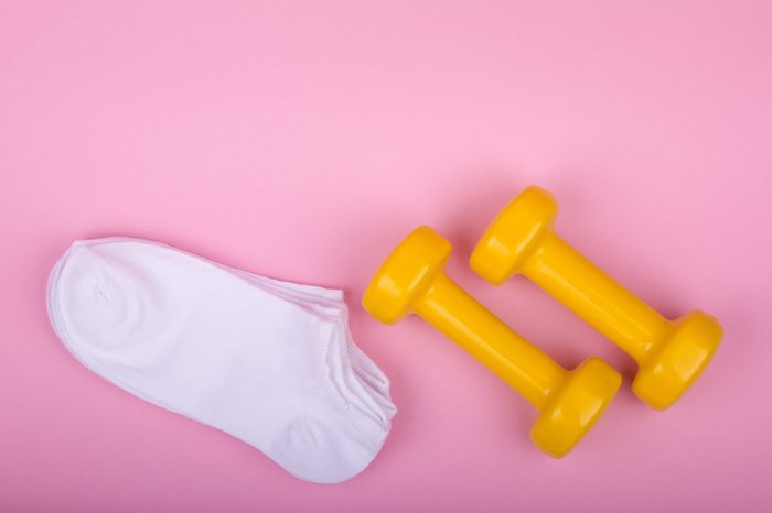 yellow dumbbells and white socks on a pink background