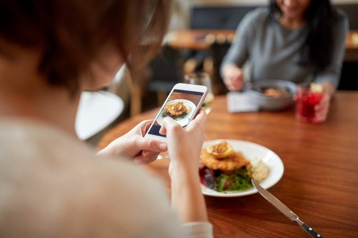 food, new nordic cuisine, technology and people concept - women with smartphones having breaded fish fillet with tartar sauce and oven-baked beetroot tomato salad for dinner at restaurant