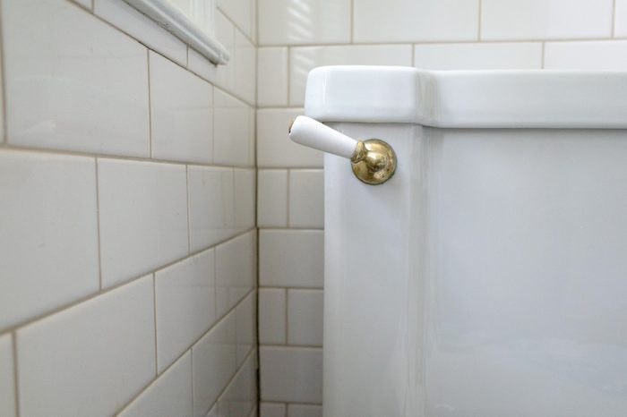 An Art Deco period toilet with porcelain and brass flush handle and vintage subway tiles