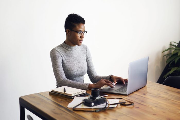 Attractive afro american businesswoman using laptop computer for working online doing distance job in coworking space,professional photographer editing pictures via application on laptop computer